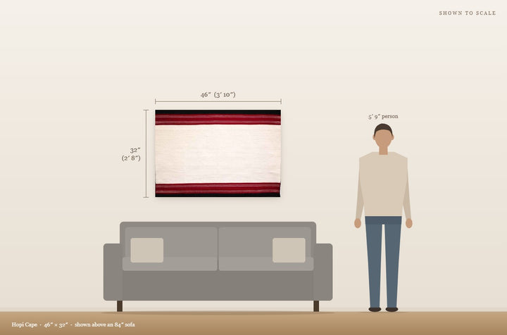 Scale view: Hopi Cape (46″ × 32″) shown on a wall above an 84″ sofa next to a 5′9″ person